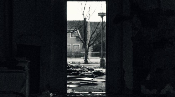 Foto: Dominik Dansc Durch einen Türrahmen blickt aus einem zertümmerten Wohnbereich auf Straße mit einem Baum in der Mitte