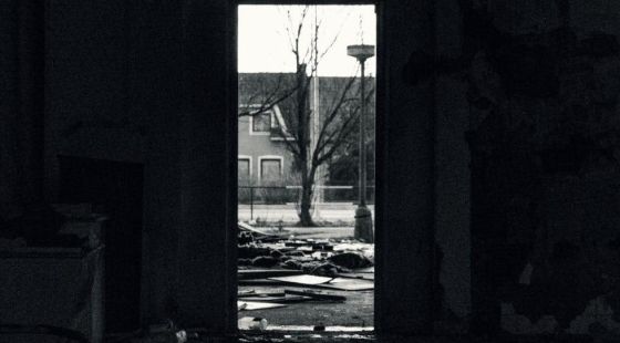 Foto: Dominik Dansc Durch einen Türrahmen blickt aus einem zertümmerten Wohnbereich auf Straße mit einem Baum in der Mitte
